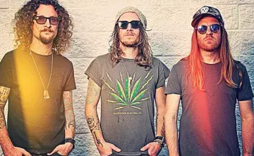 Three band members in t-shirts and sunglasses