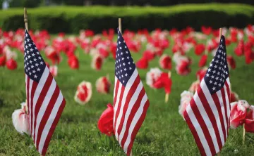 small field of  grass with American flags and flowers