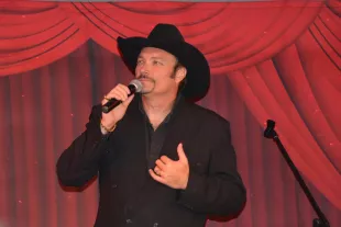 Jeff Gordon in black suit and hat with microphone