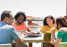 Friends eating and smiling at the beach