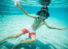 Boy with hat underwater in a pool