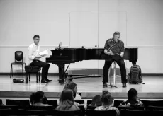 Muzika rehersal with man playing piano and another man singing