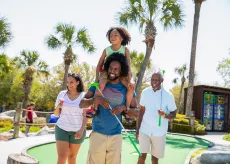 Family playing mini golf - son on dad's shoulders