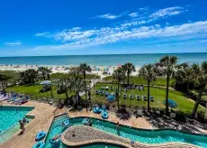 View of an outdoor lazy river and pool deck with blue inner tubes, palm trees and an exterior view of a high rise condominium