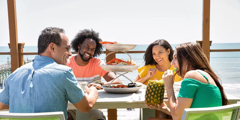 Friends eating and smiling at the beach