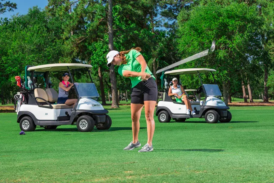 Female golf with golf carts behind her