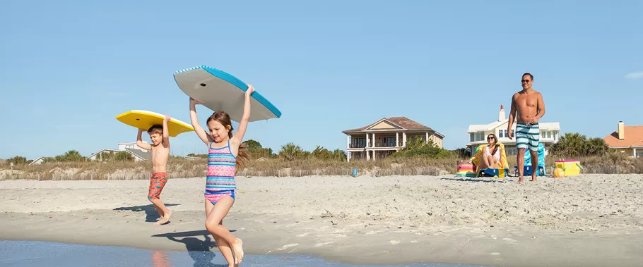 Children running to the ocean with boogie boards.