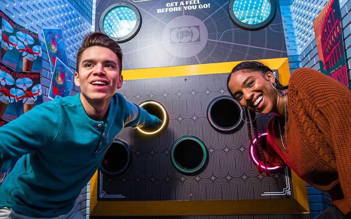 Escape Game Timeliner room two people with hands in tubes, what's in there?